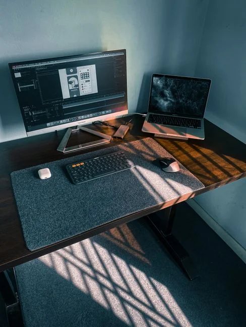 A website wireframe displayed on a MacBook screen sitting on an office desk.